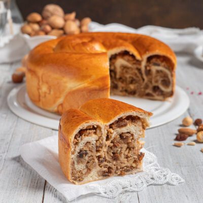 Gubana appena sfornata con una fetta tagliata che rivela il ripieno di noci e frutta secca