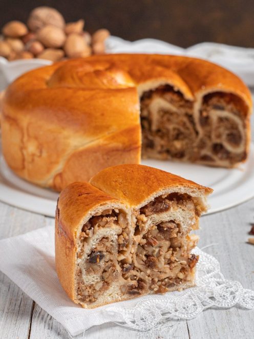 Gubana appena sfornata con una fetta tagliata che rivela il ripieno di noci e frutta secca