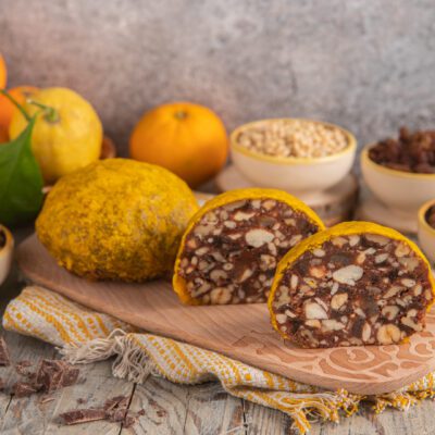 Pangiallo tagliato a metà con ripieno di frutta secca, mandorle e cioccolato, circondato dagli ingredienti