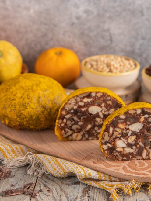 Pangiallo tagliato a metà con ripieno di frutta secca, mandorle e cioccolato, circondato dagli ingredienti