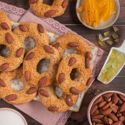 Roccocò napoletani a ciambella con mandorle intere in superficie, affiancati da scorze candite e mandorle sgusciate
