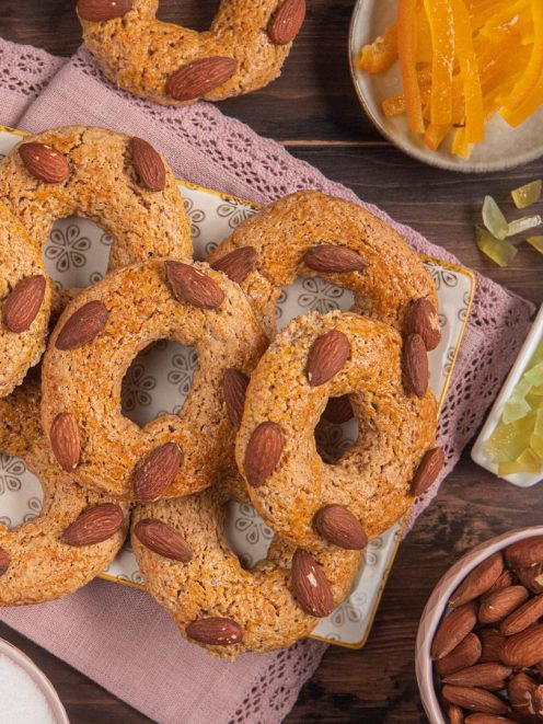 Roccocò napoletani a ciambella con mandorle intere in superficie, affiancati da scorze candite e mandorle sgusciate
