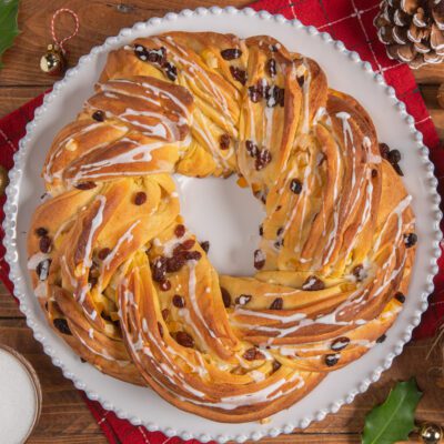 Torta angelica a corona intrecciata con uvetta e glassa bianca colata sulla superficie dorata