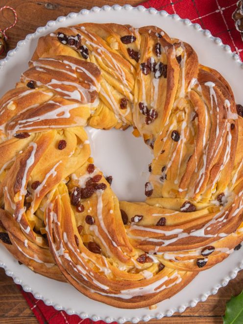 Torta angelica a corona intrecciata con uvetta e glassa bianca colata sulla superficie dorata