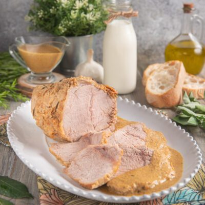 Vitello al latte affettato con la sua salsa cremosa versata a fianco delle fette