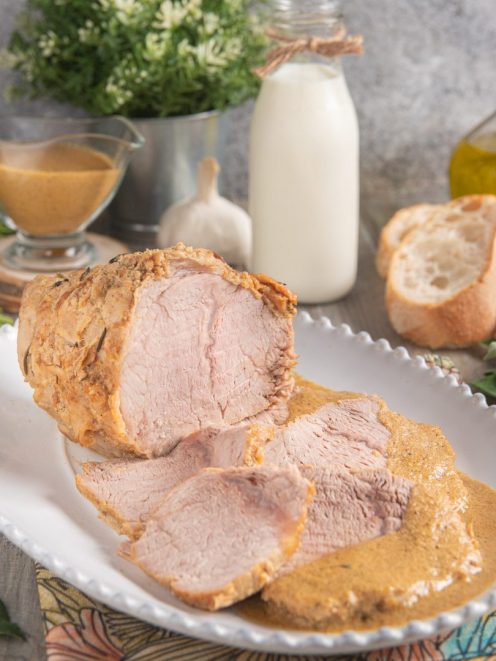 Vitello al latte affettato con la sua salsa cremosa versata a fianco delle fette