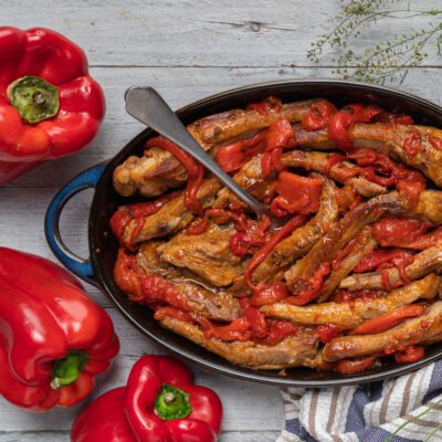 Costine di maiale ai peperoni rosolate in tegame con peperoni saltati e sugo denso