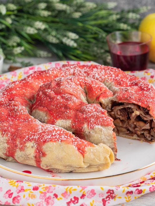 Rocciata umbra a forma di ciambella con glassa rossa e zucchero a velo, ripieno di mele e frutta secca in vista