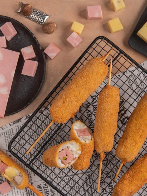 Stecchi alla petroniana fritti su stecco, uno spezzato rivela il ripieno di mortadella e formaggio