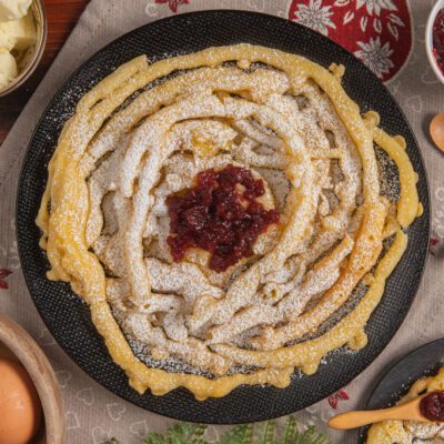 Strauben fritti a spirale spolverati di zucchero a velo con marmellata di mirtilli rossi al centro