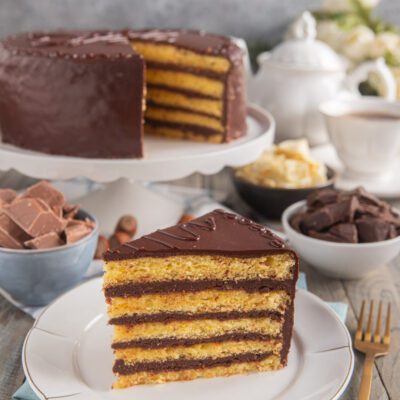 Torta Savoia a strati con pan di Spagna e crema al cioccolato, glassata e servita a fetta