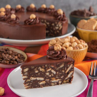 Torta salame di cioccolato al caffè in fetta, con biscotti e nocciole nell'impasto e ciuffo di crema al cioccolato