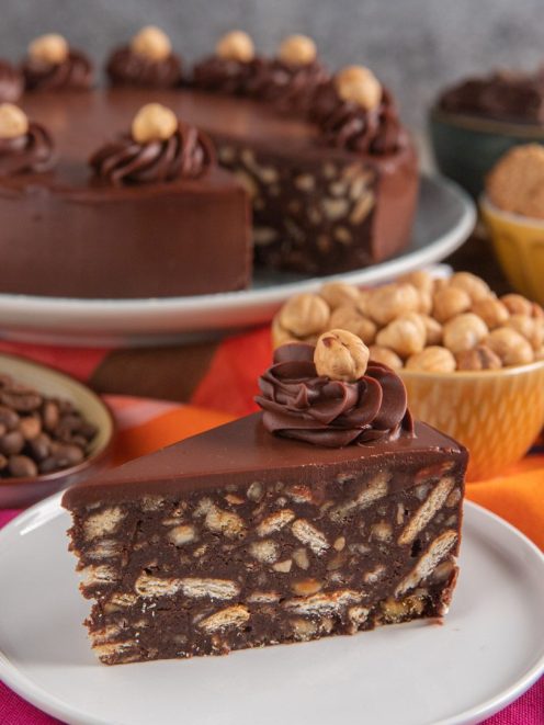 Torta salame di cioccolato al caffè in fetta, con biscotti e nocciole nell'impasto e ciuffo di crema al cioccolato
