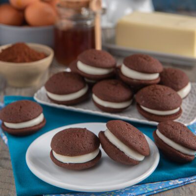 Whoopie pie al cioccolato farciti con crema bianca soffice, serviti in più porzioni