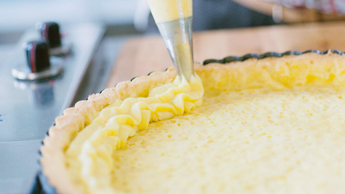 Crema pasticcera spremuta con sac-à-poche lungo il bordo della crostata