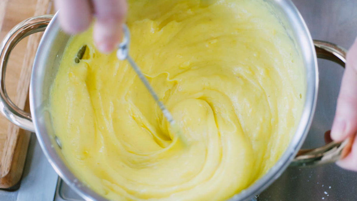 Crema pasticcera densa e liscia mescolata con una frusta in pentola