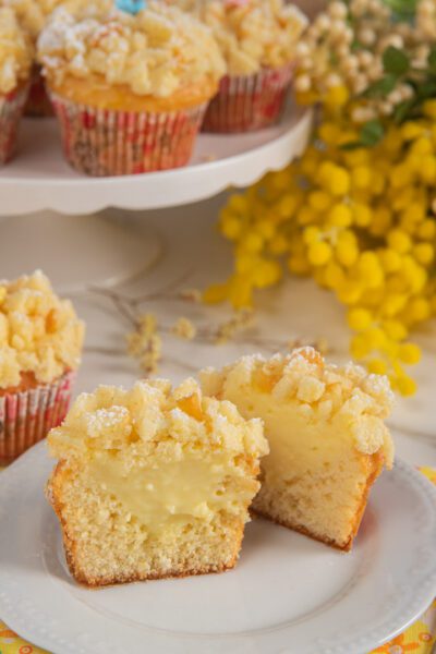 Muffin mimosa tagliato a metà con ripieno di crema al limone e copertura di briciole sbriciolate
