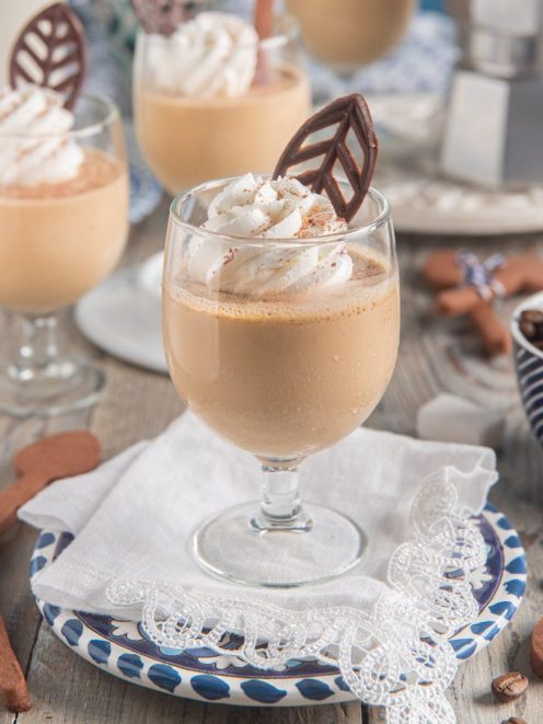 Pannacotta al caffè servita in calice con panna montata e decorazione di cioccolato a foglia