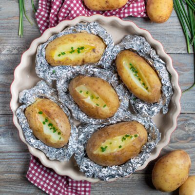 Patate al cartoccio aperte con burro fuso e erba cipollina tritata