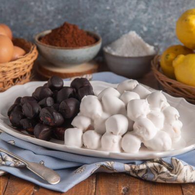 Pignolata glassata con glassa bianca al limone e glassa scura al cioccolato, servita su vassoio