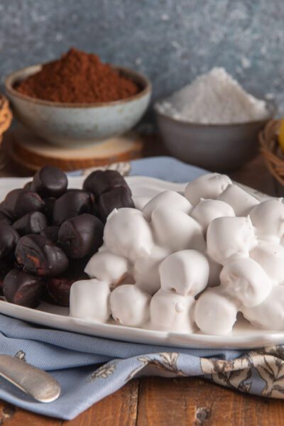 Pignolata glassata con glassa bianca al limone e glassa scura al cioccolato, servita su vassoio