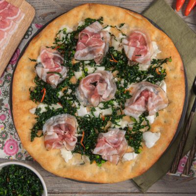 Pizza gourmet con pancetta arrotolata, cavolo nero tritato e mozzarella fior di latte