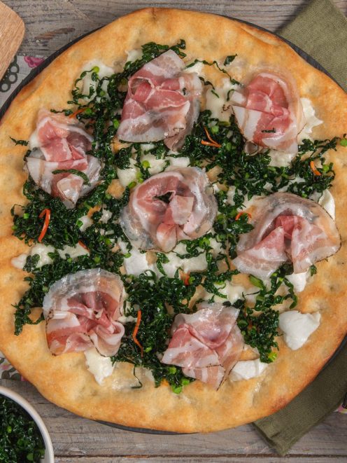Pizza gourmet con pancetta arrotolata, cavolo nero tritato e mozzarella fior di latte