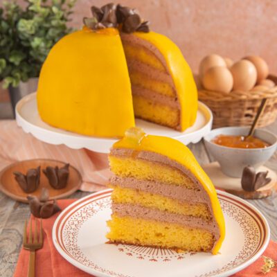 Polenta e osei a fetta con pan di spagna, crema al cioccolato e glassa gialla a forma di cupola