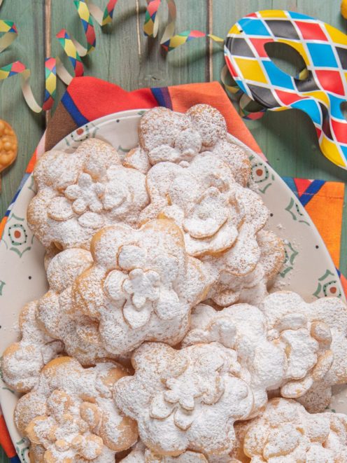 Rose di carnevale fritte a forma di fiore, impilate e abbondantemente spolverizzate di zucchero a velo