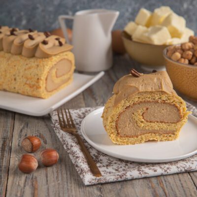 Rotolo al caffè farcito con crema al caffè, decorato con chicchi di caffè e servito a fette