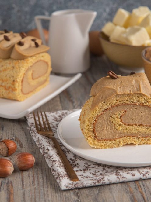 Rotolo al caffè farcito con crema al caffè, decorato con chicchi di caffè e servito a fette