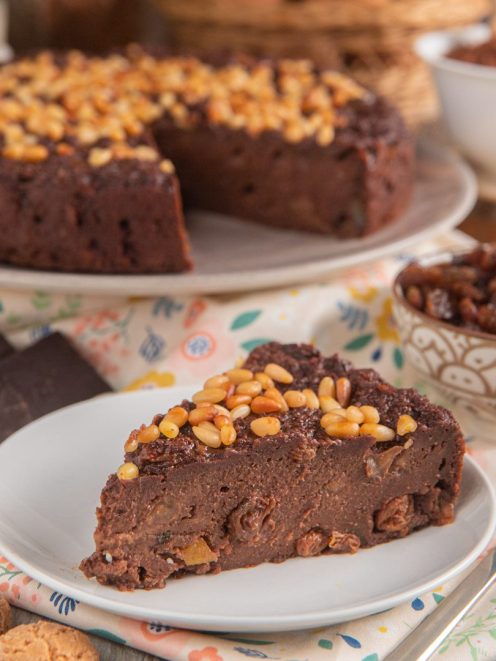 Torta paesana al cioccolato con pinoli in superficie e uvetta nell'impasto, servita a fetta