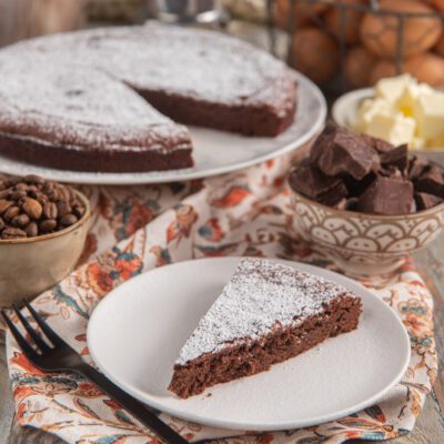 Torta tenerina al caffè con una fetta servita, spolverata di zucchero a velo