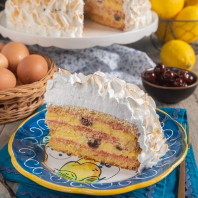 Fetta di zuppa inglese napoletana con strati di crema, amarene e meringa dorata alla fiamma