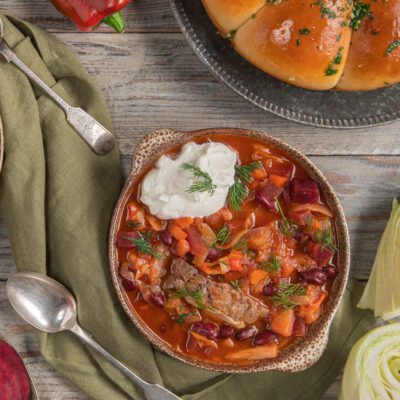 Borscht con carne, barbabietola, fagioli rossi e cavolo, guarnito con panna acida e aneto fresco
