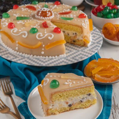 Cassata napoletana con glassa al marzapane, frutta candita colorata e una fetta che mostra il ripieno di ricotta