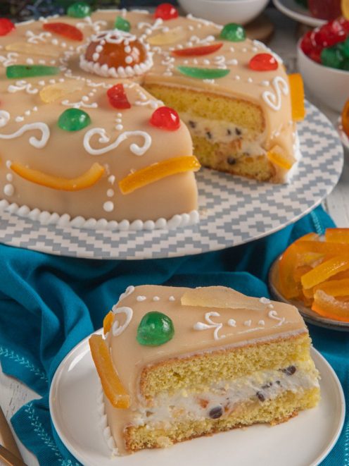 Cassata napoletana con glassa al marzapane, frutta candita colorata e una fetta che mostra il ripieno di ricotta