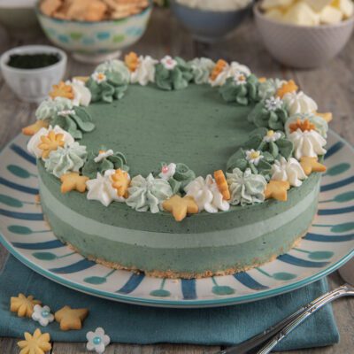 Cheesecake alla spirulina con base di biscotto, ciuffi di crema e decorazioni floreali di pasta frolla