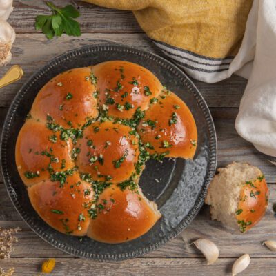 Pampushky dorati conditi con aglio tritato e prezzemolo, con un panino staccato a lato