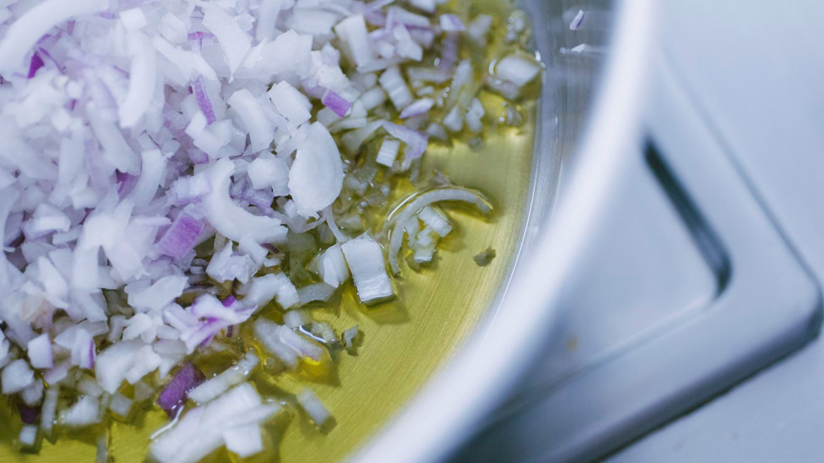 Cipolla rossa tritata finemente che appassisce nell'olio extravergine d'oliva