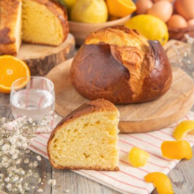 Pinza triestina con crosta dorata e mollica soffice, affiancata da scorze di agrumi