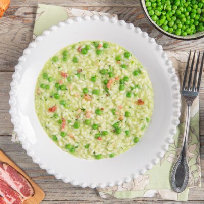 Risi e bisi cremosi con piselli freschi e pancetta a cubetti sparsi nel riso