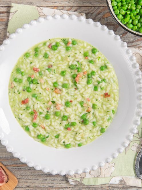 Risi e bisi cremosi con piselli freschi e pancetta a cubetti sparsi nel riso