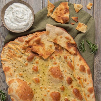 Schiacciata allo yogurt condita con olio e rosmarino, servita con salsa allo yogurt alle erbe