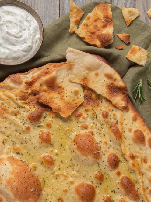 Schiacciata allo yogurt condita con olio e rosmarino, servita con salsa allo yogurt alle erbe