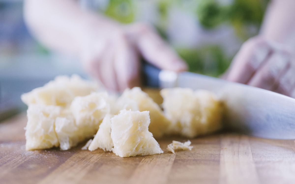 Mollica di pane spezzettata a mano sul tagliere, pronta per l'impasto delle polpette