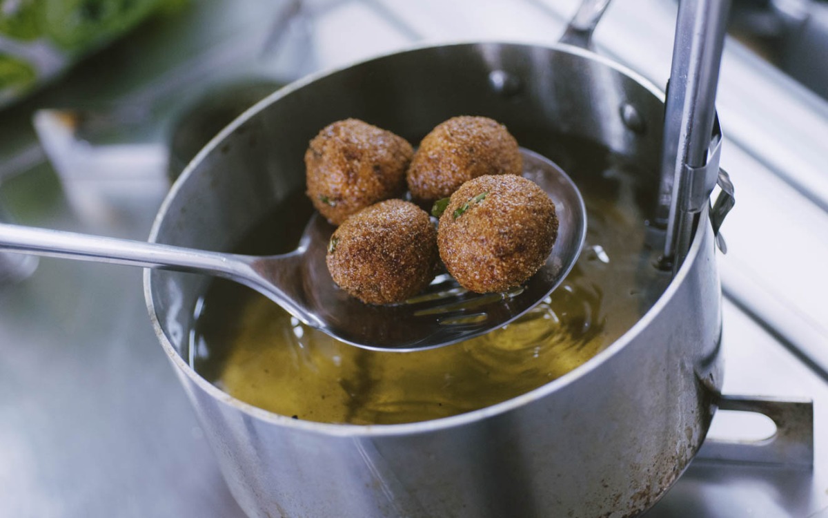 Polpette di melanzane dorate sollevate dall'olio bollente con un mestolo forato