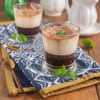 Caffè Padovano servito in tazza con strati di caffè, crema e cacao in polvere, guarnito con foglie di menta