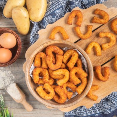Chifeletti di patate fritti a forma di ferro di cavallo, dorati e croccanti, serviti in ciotola