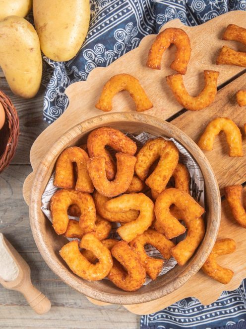 Chifeletti di patate fritti a forma di ferro di cavallo, dorati e croccanti, serviti in ciotola